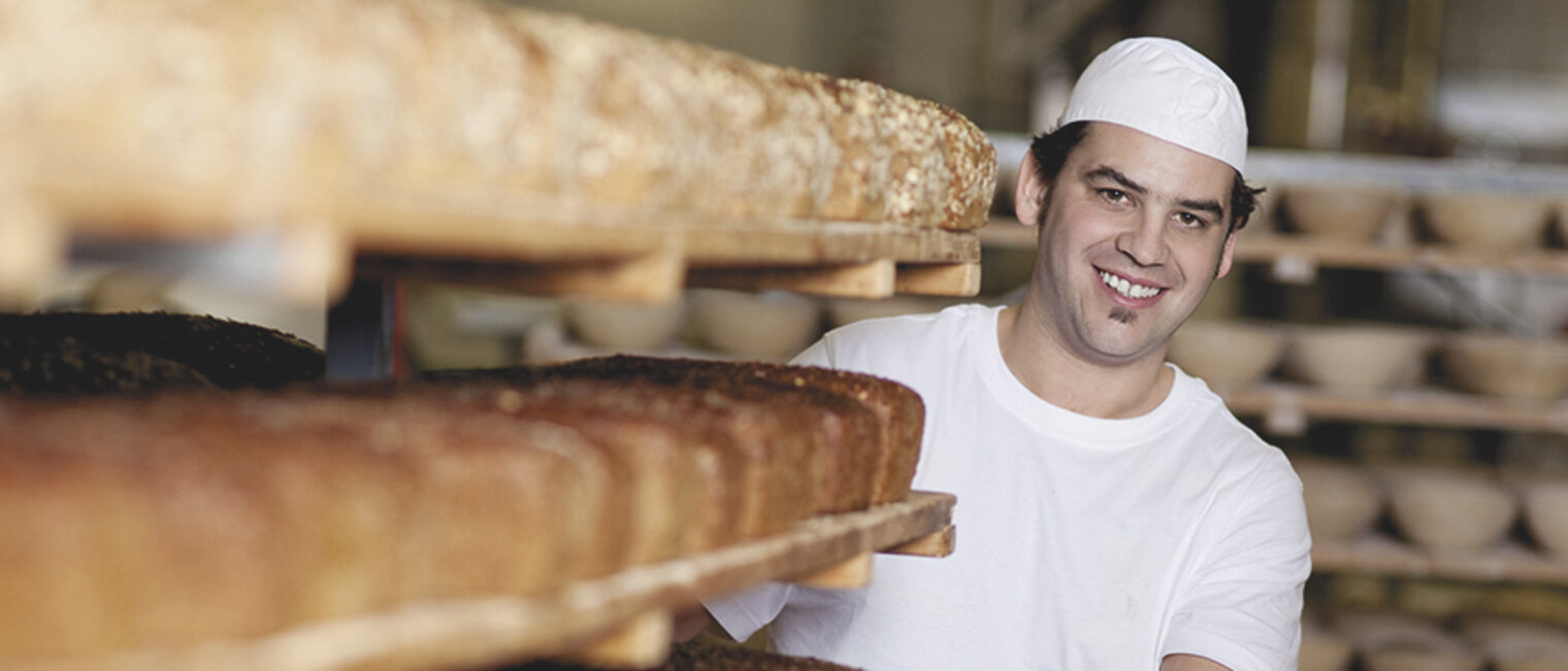 brot, bäcker, bäckerei, backwaren, mensch, person, backstube, regal, brotregal, backen, handwerk, handwerklich, gärkörbe, produktion, herstellung, qualität, verkauf, verkaufen, laib, brotlaib, lebensmittel, sortiment, genuss, genießen, lecker, gebacken, angebot, ernährung, ballaststoffe, gesund, gesundheit, weizen, getreide, korn, kruste, knusprig, nahrungsmittel, rund, kaufen, mehl, frisch, frische, holzregal, mann, zufrieden, lachen, lächeln, 30-40