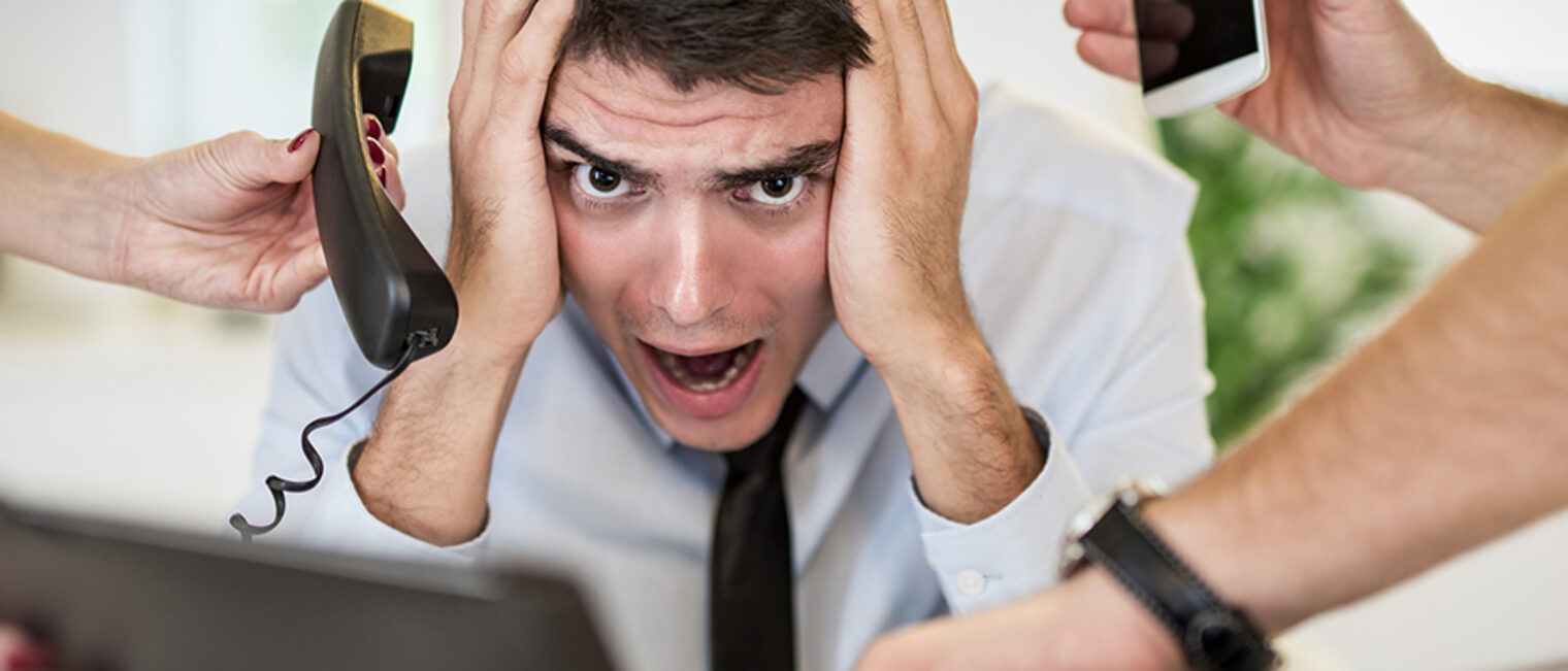 Stressed busineessman sorounded with many jobs. Schlagwort(e): businessman, overworked, office, frustrated, work, stress, time, headache, multitasking, Physical Pressure, busy, phone, upset, anger, Shouting, Worried, Distraught, hand, young, horizontal